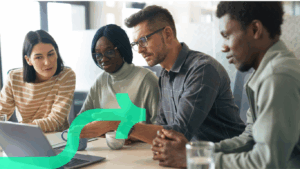 Team of diverse professionals collaborating around a laptop during a Discflow leadership workshop, discussing communication and leadership styles.
